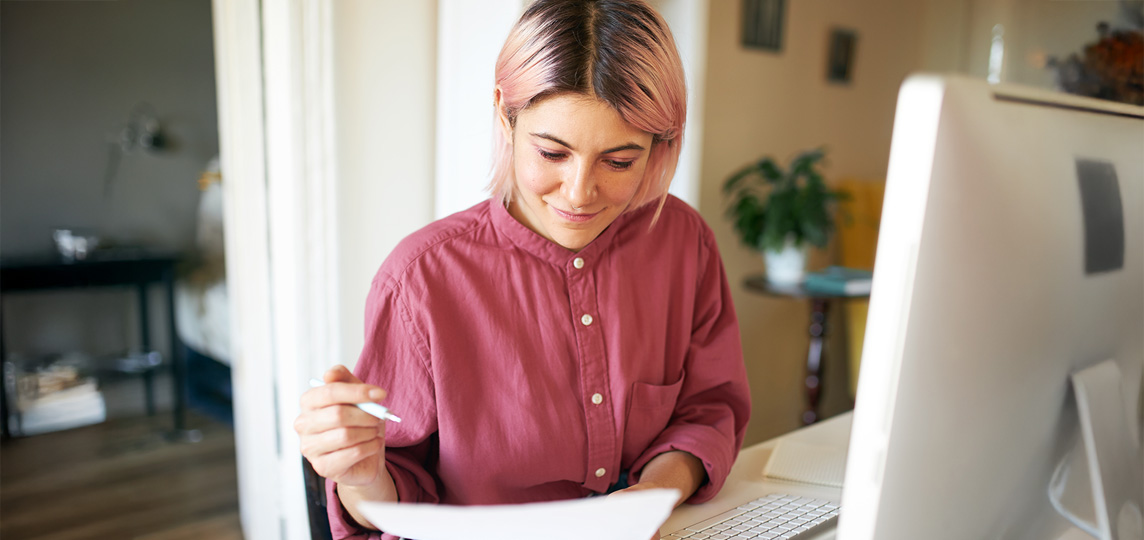 young girl learning using paper notes and computer for elearning