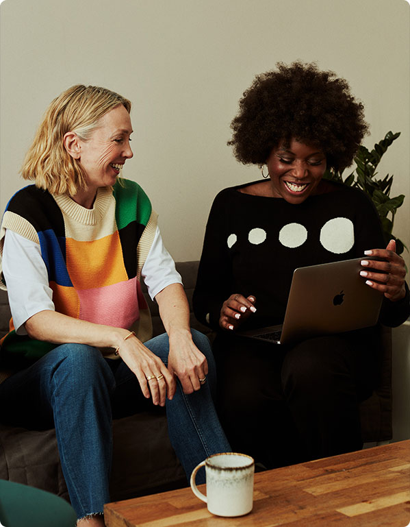 two female colleagues smiling with a laptop