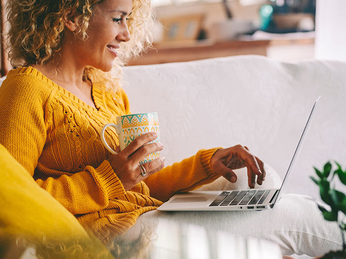 A woman using a laptop for learning while drinking a cup of tea